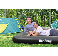 Ein Paar entspannt auf einer Luftmatratze beim Camping im Wald, Zelte im Hintergrund