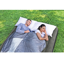 Zwei Personen schlafen auf einer Luftmatratze mit Schlafsack und Kissen im Freien.