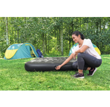 Frau bereitet eine Luftmatratze zum Campen vor einem Zelt vor.
