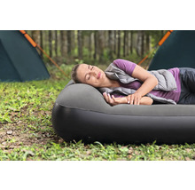 Frau schläft auf Luftmatratze auf einem Campingplatz.