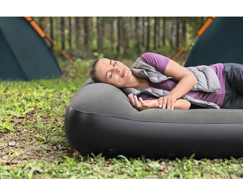 Frau schläft auf Luftmatratze auf einem Campingplatz.
