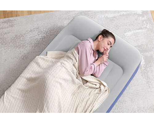 Frau schläft auf einer Luftmatratze mit Decke auf einem Teppich