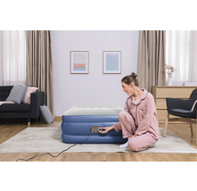 Frau bereitet Luftmatratze mit eingebauter Pumpe im Wohnzimmer vor.