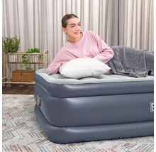 Frau entspannt auf Luftbett mit Kissen und Decke im Wohnzimmer.