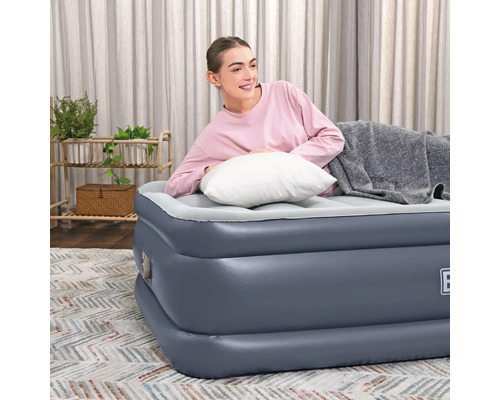 Frau entspannt auf Luftbett mit Kissen und Decke im Wohnzimmer.