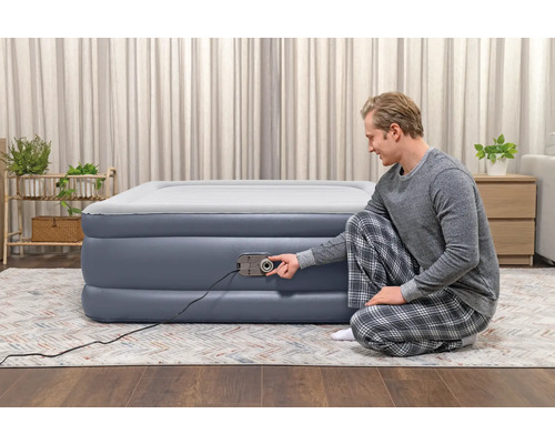 Mann benutzt ein aufblasbares Gästebett mit integrierter Pumpe im Innenraum.