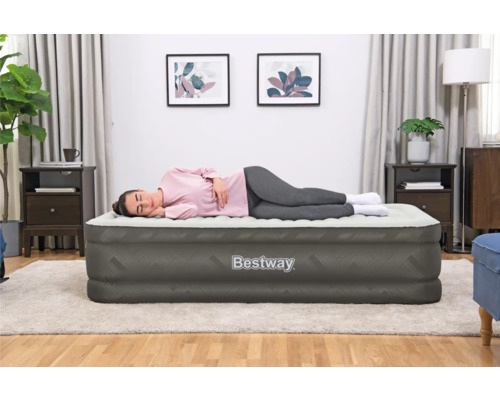 Frau liegt auf einer grauen Bestway Luftmatratze im Zimmer.