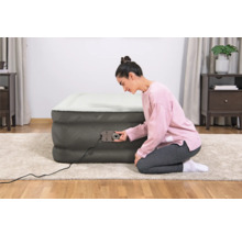 Frau bedient eine Luftmatratze mit integrierter Pumpe im Innenraum.