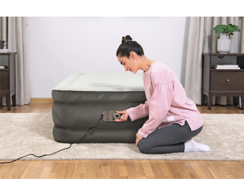 Frau bedient eine Luftmatratze mit integrierter Pumpe im Innenraum.