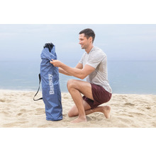 Mann öffnet eine Tragetasche für einen Strandsitz der Marke Bestway am Strand