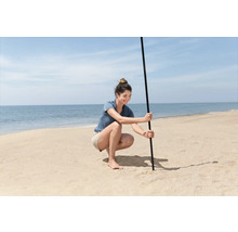 Frau befestigt Sonnenschirm am Strand