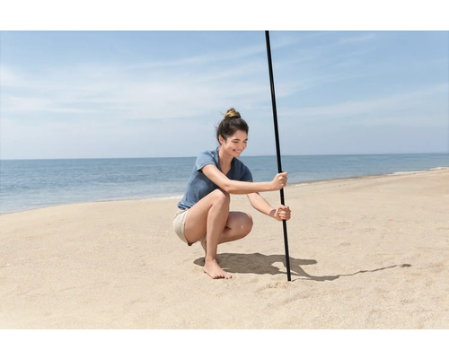 Frau befestigt Sonnenschirm am Strand