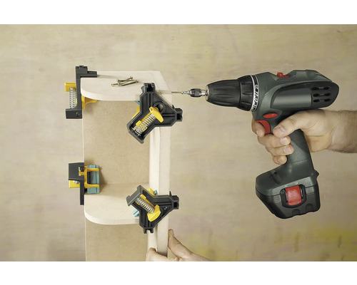 Eine Werkstattszene zeigt eine Ecke aus Holz, die mit Eckspannzwingen befestigt und von einem Akkuschrauber verschraubt wird.