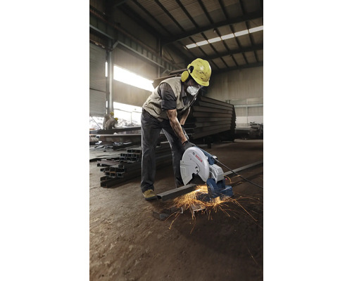 Ein Arbeiter benutzt eine Metalltrennsäge in einer Werkshalle.