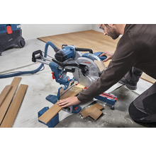 Ein Mann bedient eine Kappsäge zum Schneiden von Holz in einer Werkstatt.