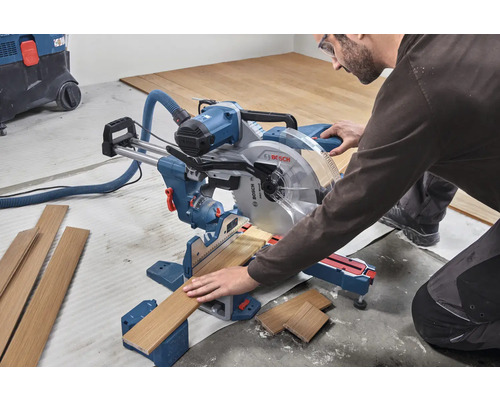 Ein Mann bedient eine Kappsäge zum Schneiden von Holz in einer Werkstatt.