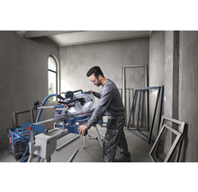 Mann arbeitet mit einer Kapp- und Gehrungssäge in einem Raum mit Fensterrahmen.