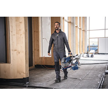 Ein Handwerker trägt eine Kappsäge in einem Rohbau.