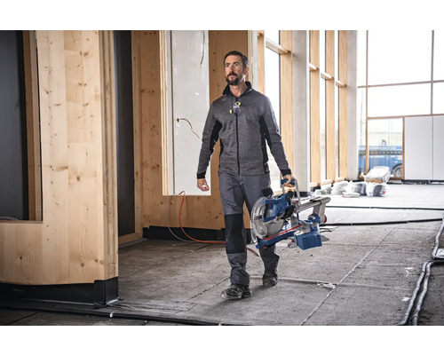 Ein Handwerker trägt eine Kappsäge in einem Rohbau.