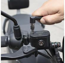 Eine Person verwendet einen Schraubendreher mit Winkelvorsatz, um an einem Motorrad zu arbeiten.