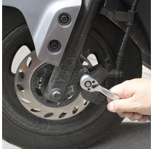 Eine Person benutzt eine Knarre am Motorrad.