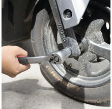 Hand, die eine Knarre an einem Rad befestigt.