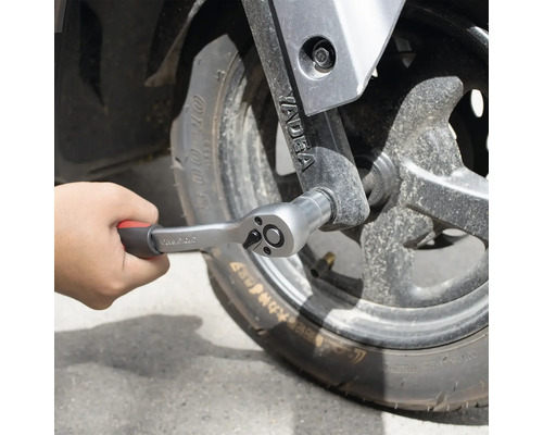 Hand, die eine Knarre an einem Rad befestigt.