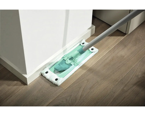 Bodenwischer mit Mikrofaserbezug beim Reinigen eines Holzbodens an einer weißen Wand.