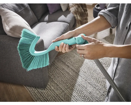 Staubwedel mit Teleskopstiel wird an einem Sofa verwendet