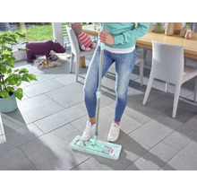 Frau wischt Fliesenboden mit einem Mopp