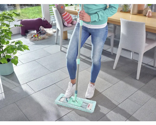 Frau wischt Fliesenboden mit einem Mopp