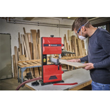 Ein Mann bedient eine rote Bandsäge mit Einhell Logo in einer Werkstatt.