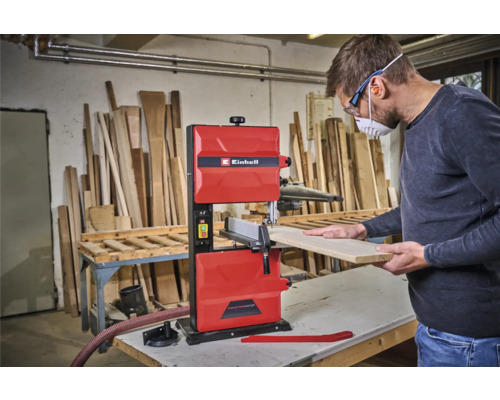 Ein Mann bedient eine rote Bandsäge mit Einhell Logo in einer Werkstatt.
