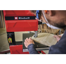 Ein Mann benutzt eine Einhell Bandsäge, um ein Stück Holz zu schneiden.