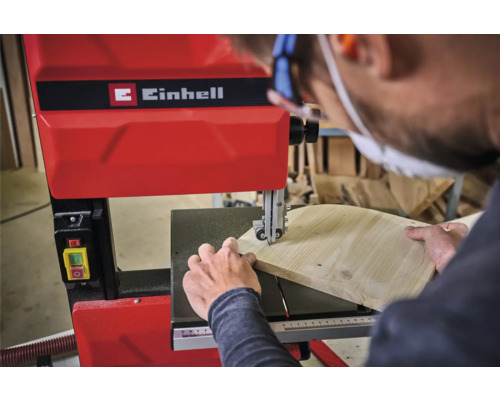 Ein Mann benutzt eine Einhell Bandsäge, um ein Stück Holz zu schneiden.