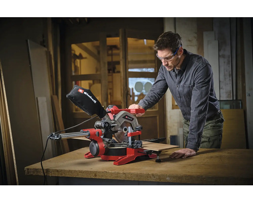 Mann bedient eine rote Einhell Kapp- und Gehrungssäge mit Werkstück