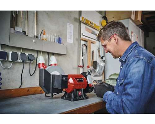 Mann arbeitet mit einer Einhell Doppelschleifmaschine in einer Werkstatt