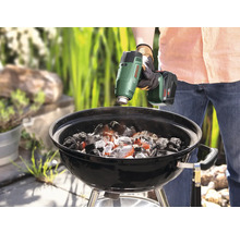 Anzünden von Grillkohle mit einem Akku-Heißluftgebläse in einem Holzkohlegrill.