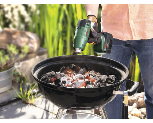 Anzünden von Grillkohle mit einem Akku-Heißluftgebläse in einem Holzkohlegrill.
