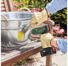 Bosch EasyHeat 18V-500 Heißluftpistole im Einsatz zum Entfernen eines Etiketts von einem Zinkeimer.