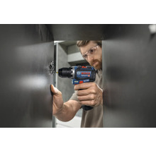 Mann schraubt Scharnier mit Akku-Bohrschrauber an eine Tür.