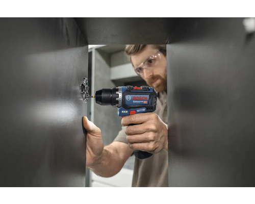 Mann schraubt Scharnier mit Akku-Bohrschrauber an eine Tür.