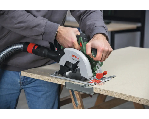 Bosch Handkreissäge beim Sägen einer Holzplatte mit Staubabsaugung