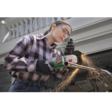 Frau mit Schutzbrille und Handschuhen beim Schleifen eines Metallrohrs mit einem Winkelschleifer.