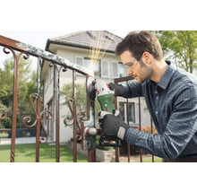 Ein Mann schleift mit einer Schleifmaschine ein Metalltor im Freien.