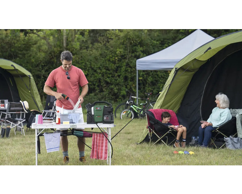 Campingszene mit Person, die Geschirr spült, Zelten und Sitzgelegenheiten