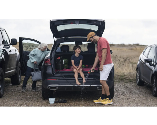 Szene mit Familie, die sich nach einem Ausflug im Freien die Füße mit einem Gartenschlauch reinigt.