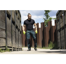 Mann in Arbeitskleidung mit Arbeitshose und Arbeitshandschuhen im Freien