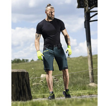 Mann trägt Arbeitsshorts, T-Shirt, Handschuhe und Sicherheitsschuhe im Freien