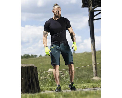 Mann trägt Arbeitsshorts, T-Shirt und Arbeitshandschuhe im Freien